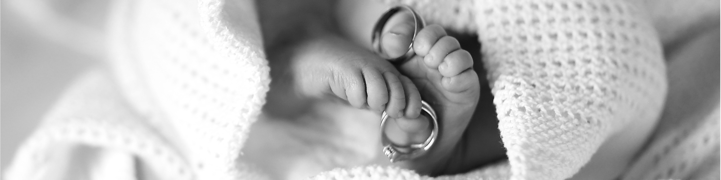 Black and white photograph of Baby feet and wedding rings